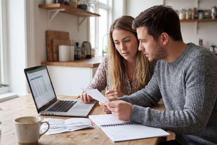 A couple sitting at a desktop in their home looking and comparing their Employer’s Health Plan for the ACA Marketplace